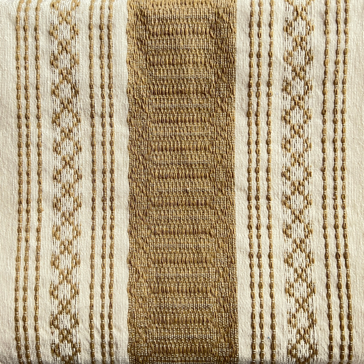Close up view of a tan and natural striped woven table runner with tassels