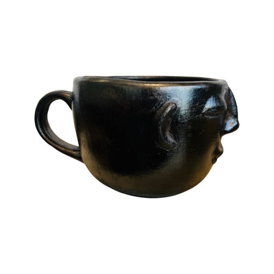 side view of black clay colored mug hand sculpted with facial features
