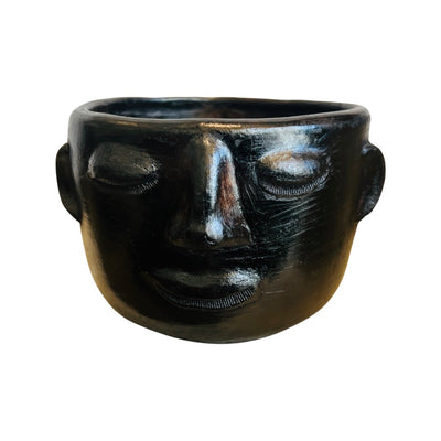 front view of black clay colored mug hand sculpted with facial features