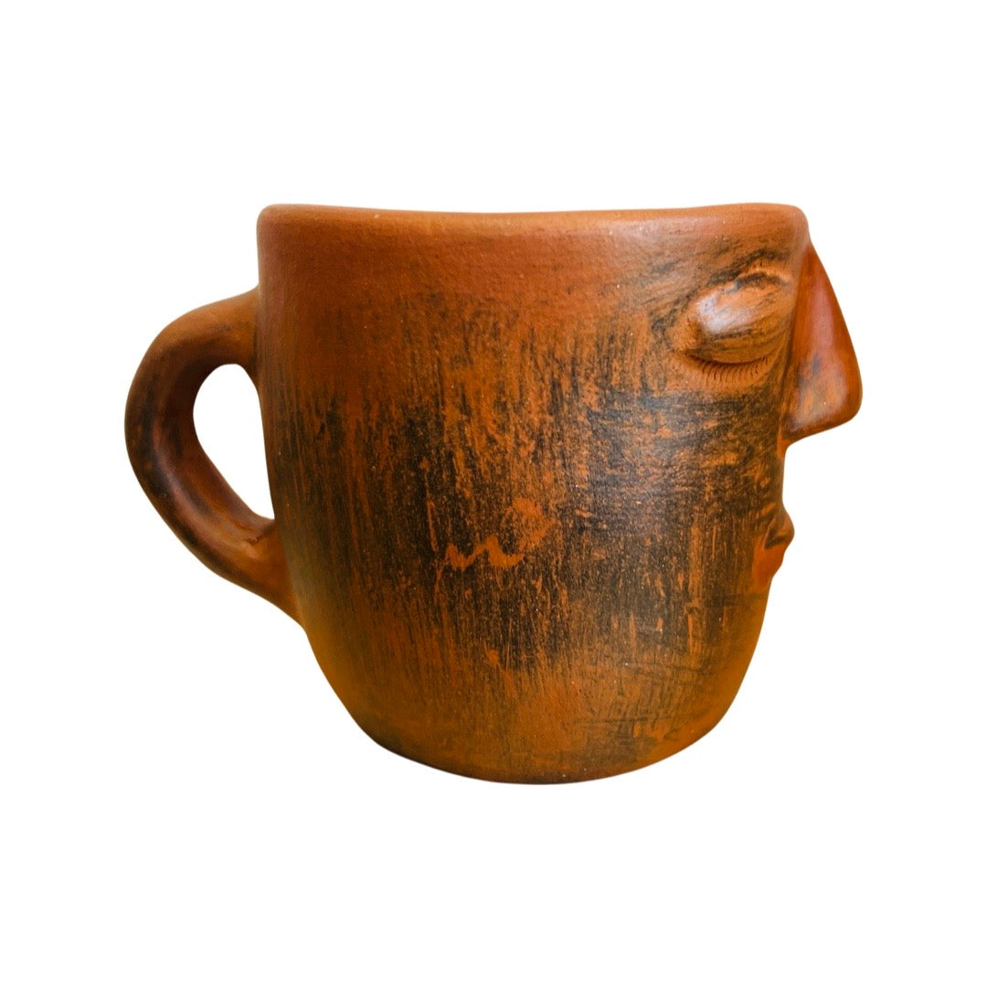 side view of clay colored mug hand sculpted with facial features
