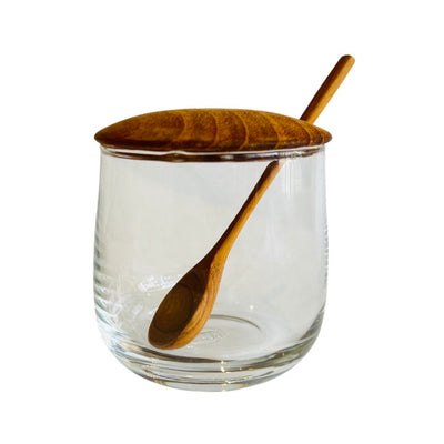 Glass jar with teak lid and wooden spoon.
