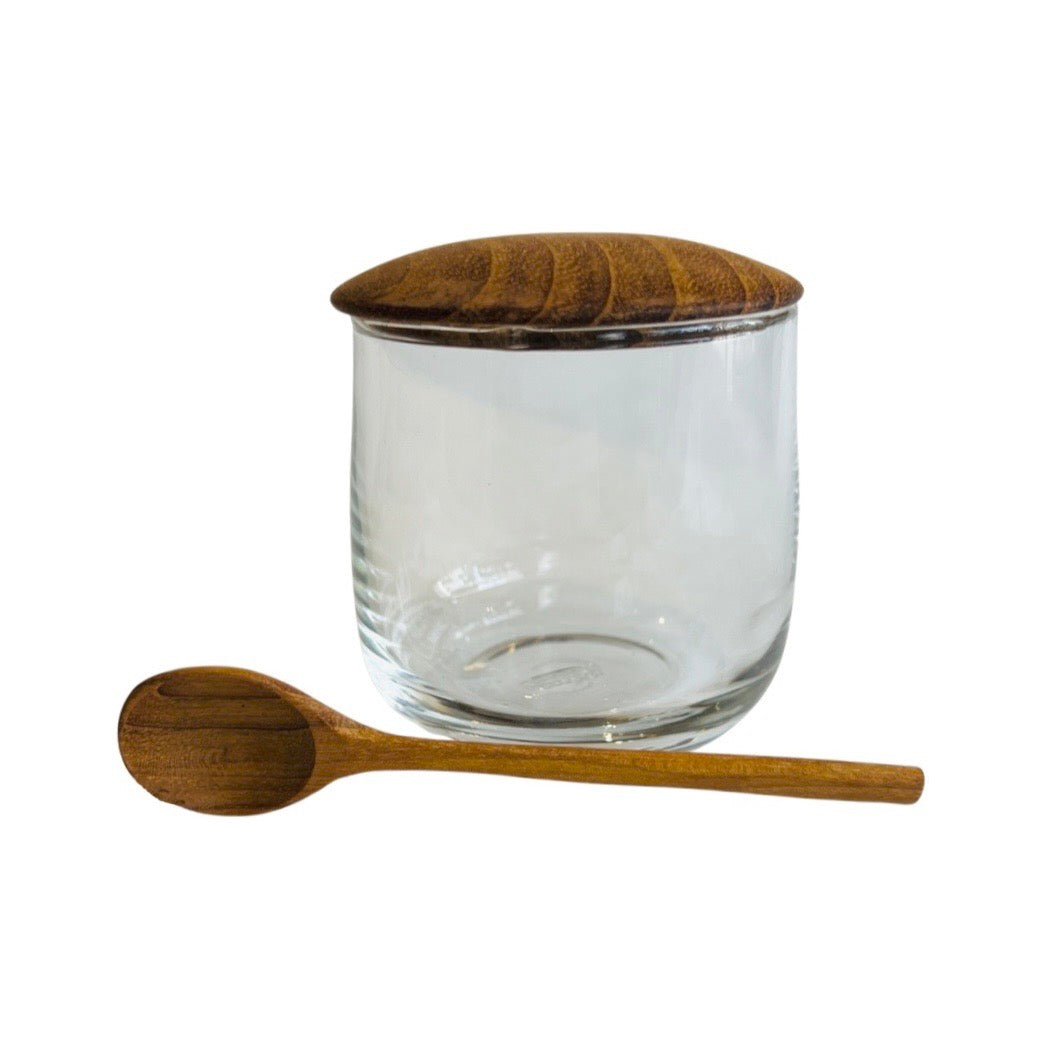 Glass jar with teak lid and wooden spoon shown outside the jar.