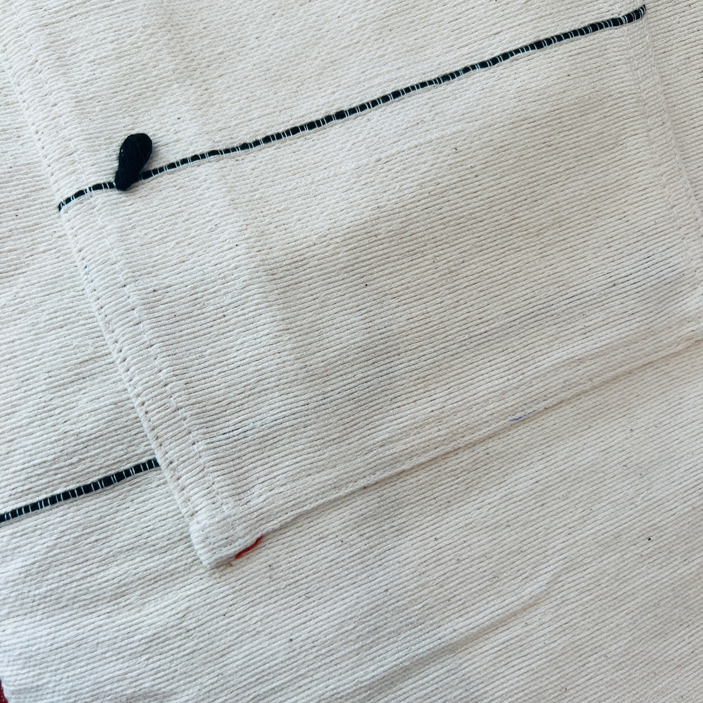 Close up of Cream cotton woven apron with two front pockets