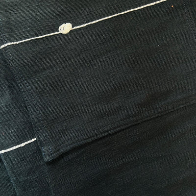 Close up of a black cotton woven apron with two front pockets