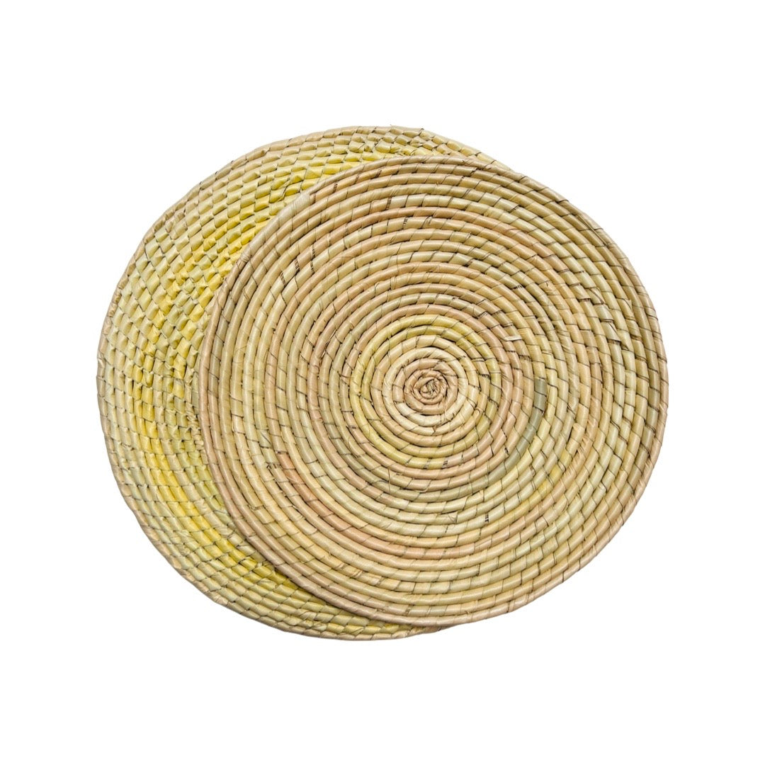 12" & 14" Natural colored circular woven palm placemat laid on top of eachother