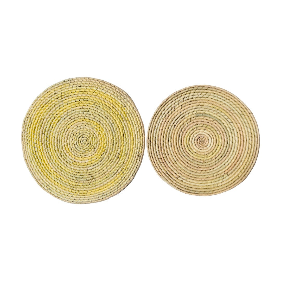 12" & 14" Natural colored circular woven palm placemats laid side by side