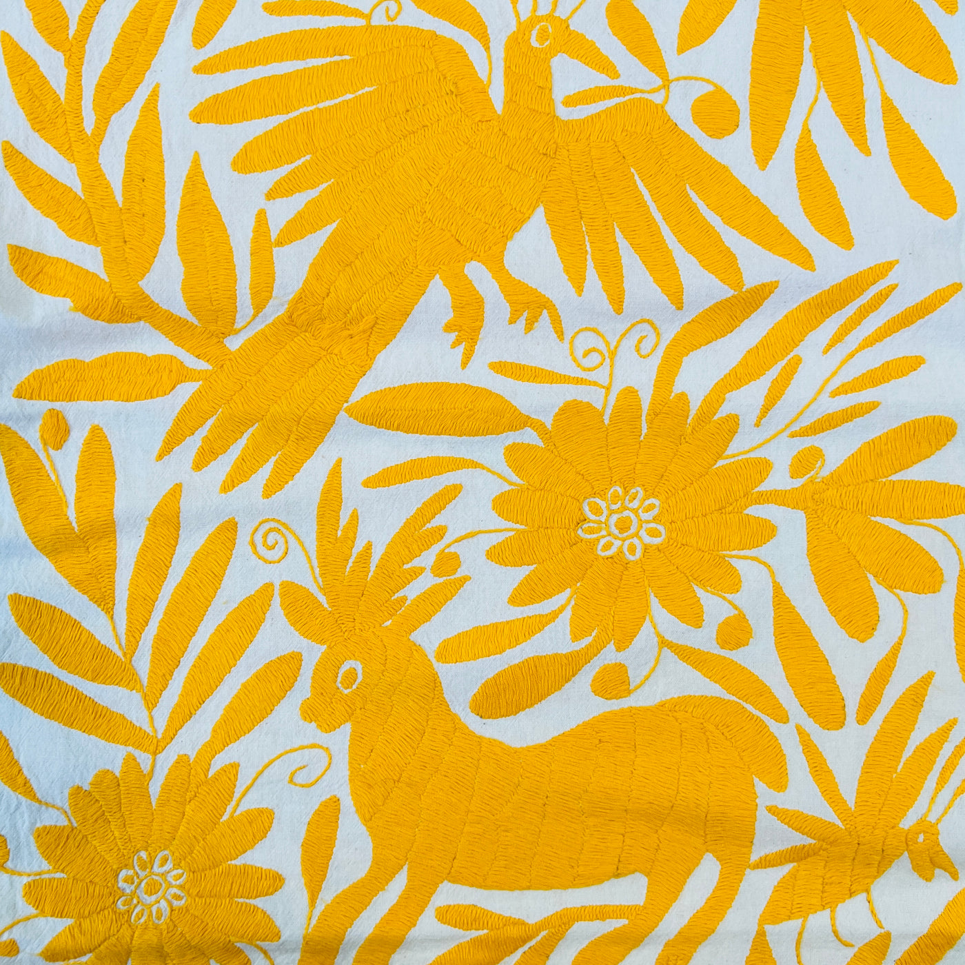 enhanced view of yellow floral and fauna scenery detail embroidered on off white table runner
