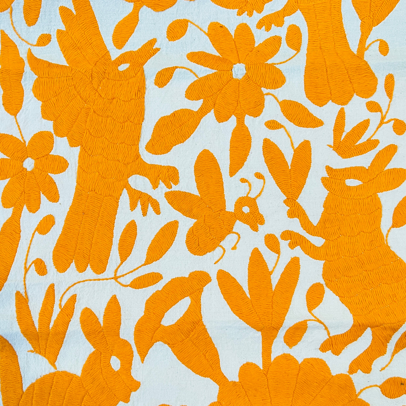 enhanced view of orange floral and fauna scenery detail embroidered on off white table runner