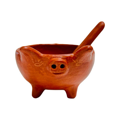 front view of red clay handsculpted spoon and bowl with pig legs and pig facial features