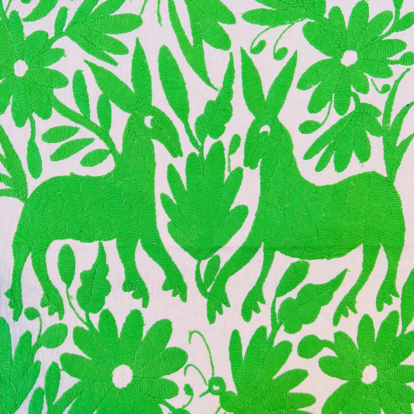 enhanced view of green floral and fauna scenery detail embroidered on off white table runner