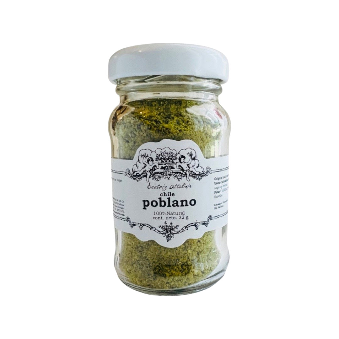A clear jar of 32 g. dried and ground chile poblano peppers. Label is white with black lettering and an image of two cherubs in the garden with the clouds behind them.  