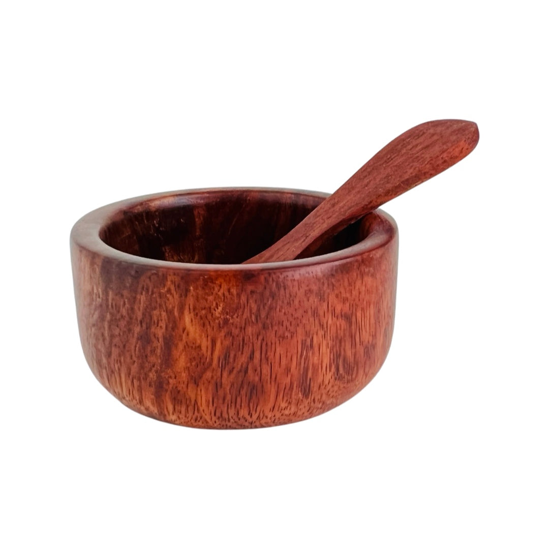  side view of circular bowl carved from wood with wooden spoon
