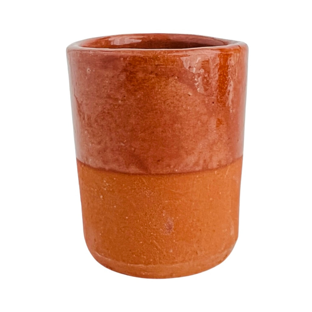 front view of red clay shot glass, top half is glossy due to glaze, bottom half is unglazed and matte finish