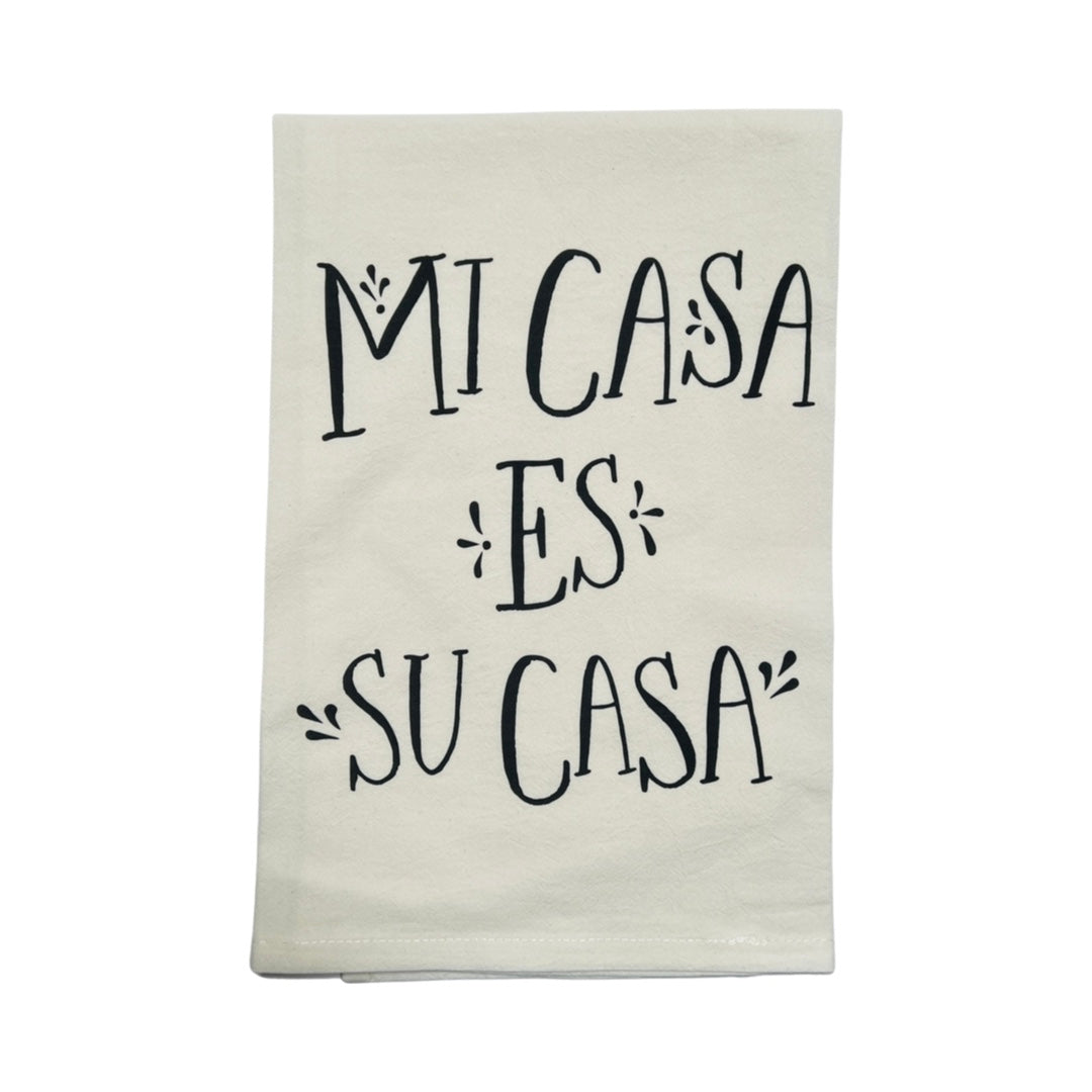 folded off white cotton towel with printed graphic reading "Mi Casa Es Su Casa"