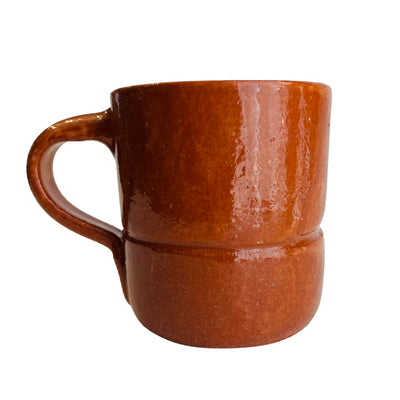side view of red clay mug, handle is shown