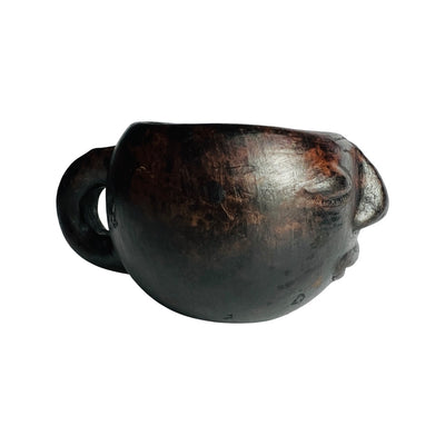 side view of black clay colored mug hand sculpted with facial features