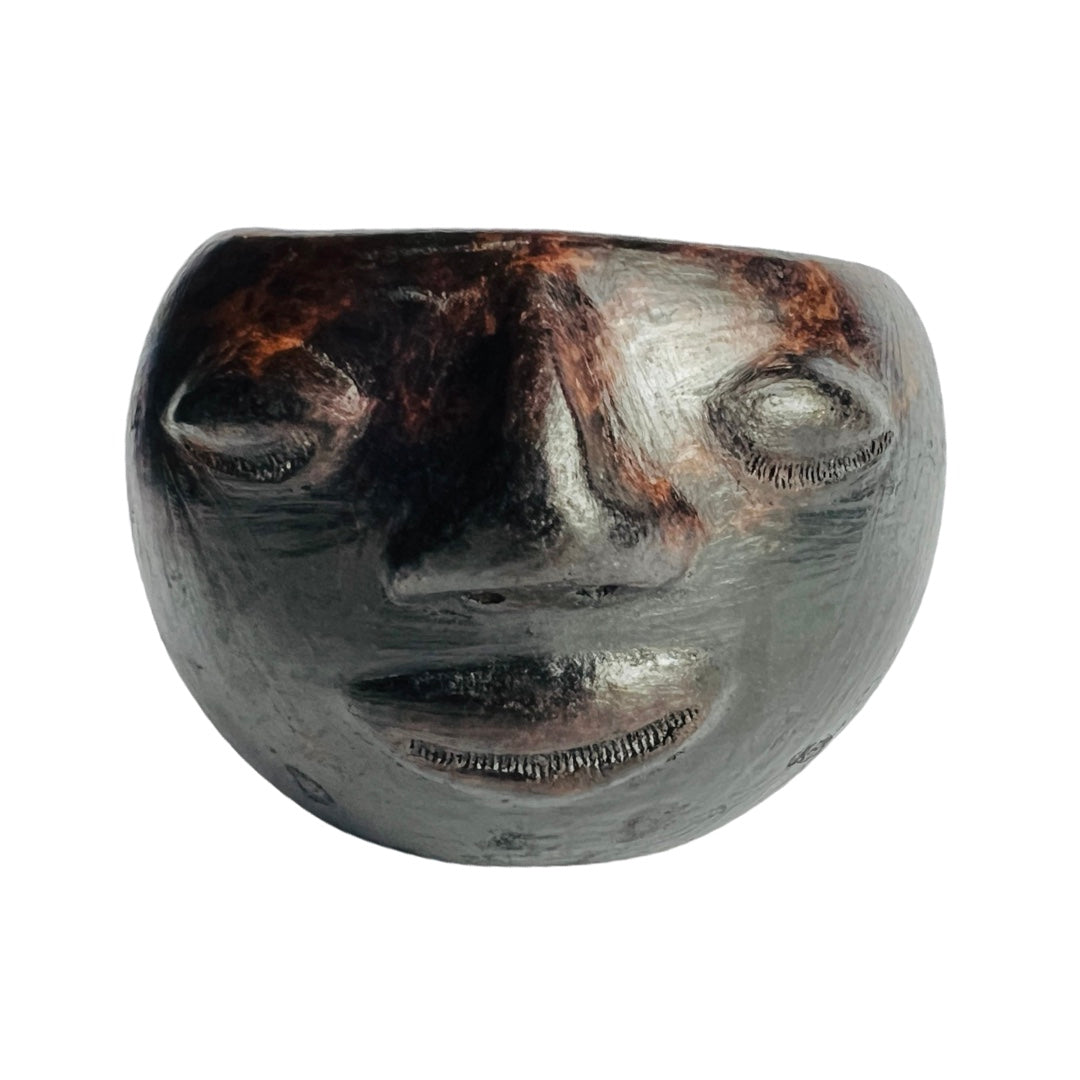 front view of black clay colored mug hand sculpted with facial features