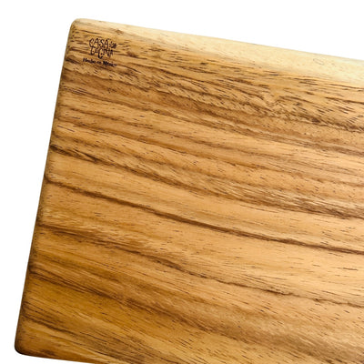 Close up view of a rectangular wooden cutting board with the phrase Casa Y Cocina engraved on the top left corner.  Translation for Casa y Cocina is Home and Kitchen. 
